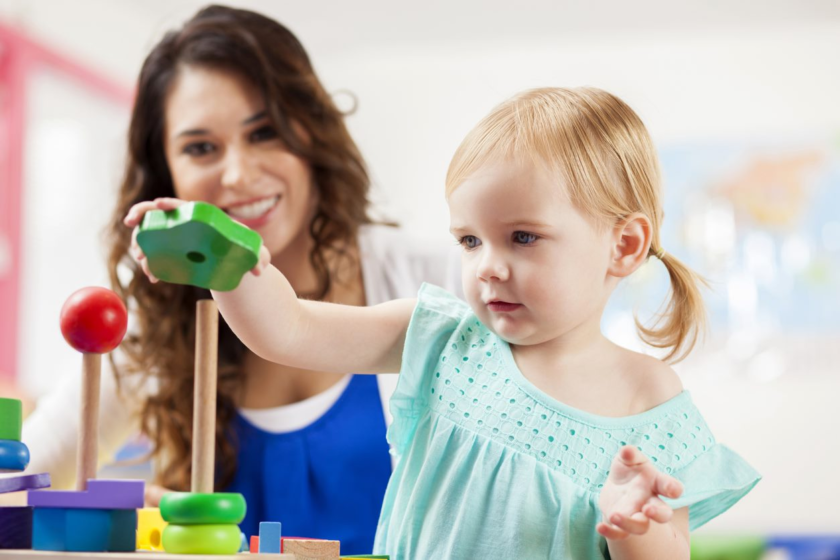 teacher watching child play with blocks.